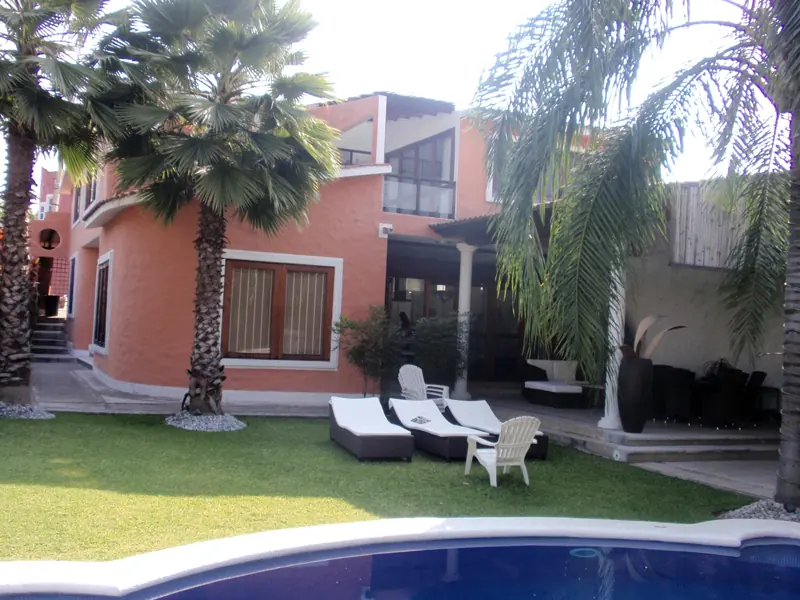Jardín con palmeras frente a la fachada de una residencia