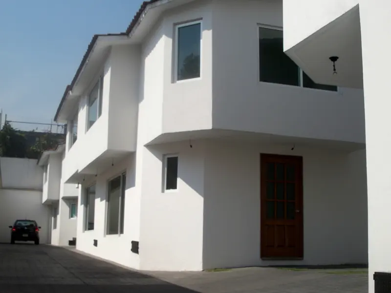 Conjunto de casas blancas de dos niveles con acceso vehicular